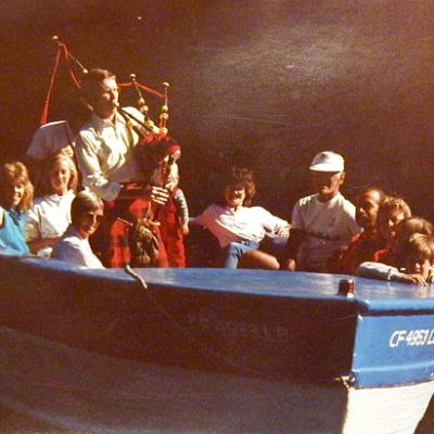 Highland piper in the old Boy Scout boat, Bluto. Kathleen on portside